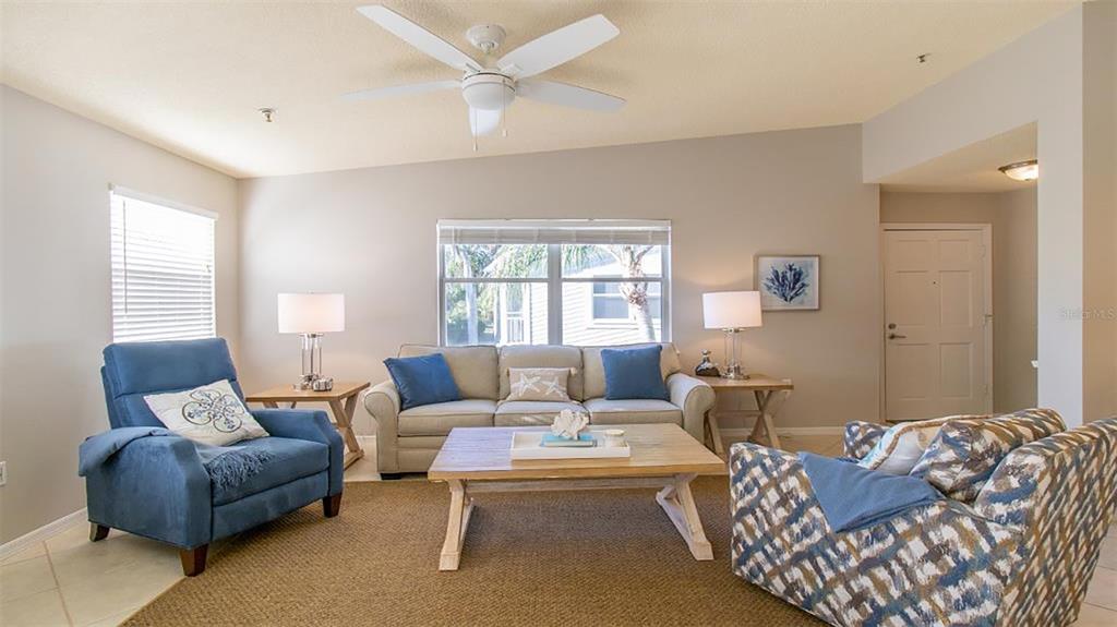 A living room features a blue armchair, a beige sofa, and a patterned accent chair — 1340 SIESTA BAYSIDE DRIVE UNIT 1340-C, SARASOTA, FL