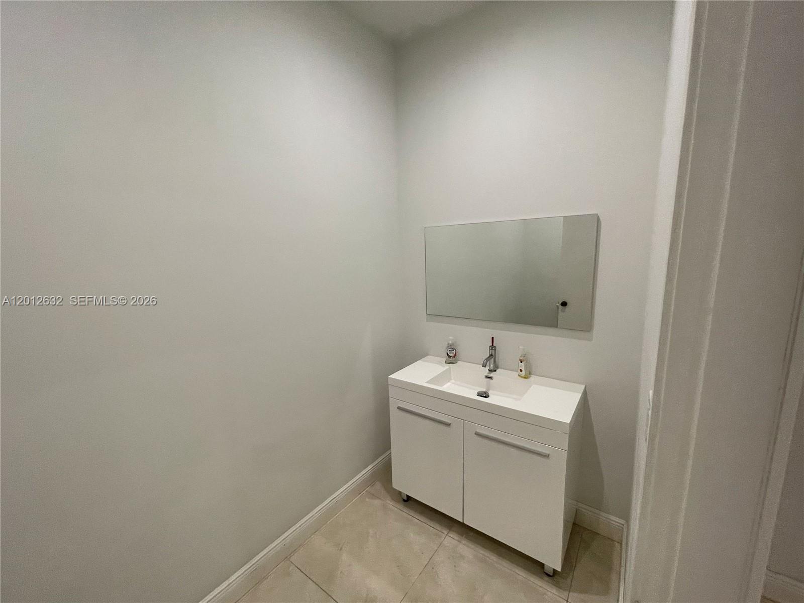 A small bathroom features a white vanity cabinet, a rectangular mirror, and light-colored tile flooring — 3004 NW 79th Ave # 3004, Doral FL 33122, DORAL, FL