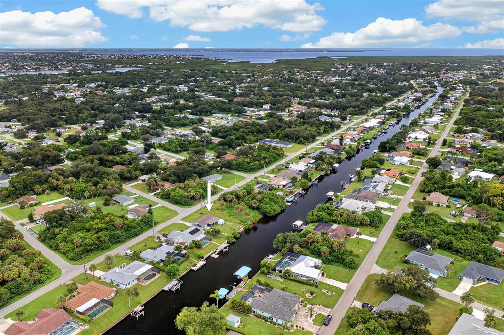 An aerial view shows a residential neighborhood with houses lining a canal leading toward water — 3165 ROCK CREEK DRIVE, PORT CHARLOTTE, FL