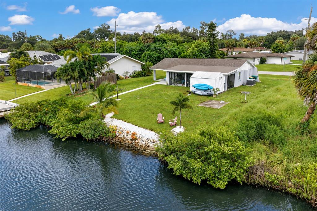 An aerial view of a waterfront house with a grassy yard, kayaks, and palm trees — 3165 ROCK CREEK DRIVE, PORT CHARLOTTE, FL