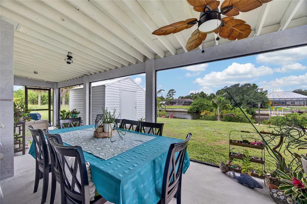 A screened-in patio features a dining table, a ceiling fan, and a view of water — 3165 ROCK CREEK DRIVE, PORT CHARLOTTE, FL