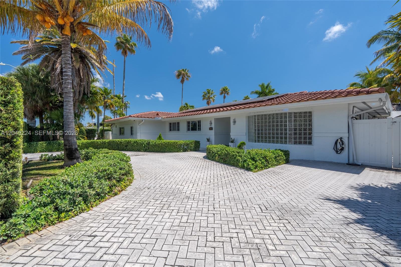 A white house with a tiled roof and a paved driveway surrounded by palm trees — 20235 Highland Lakes Blvd, Miami FL 33179, MIAMI, FL