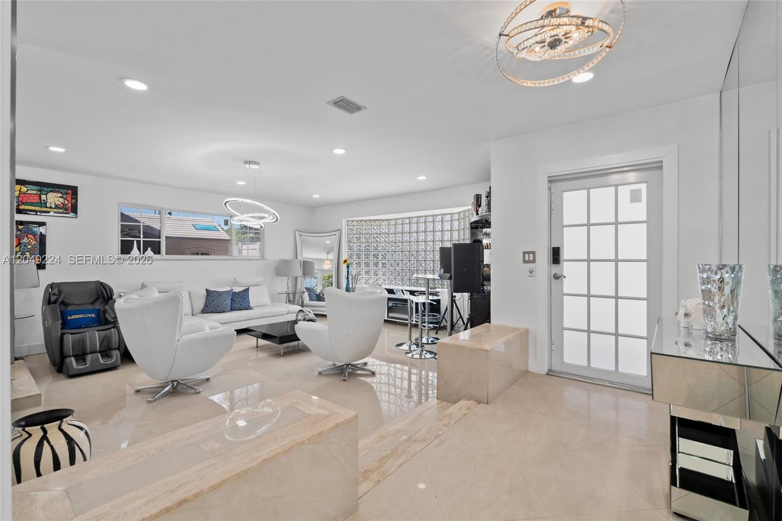 A bright living room features white furniture, a glass block wall, and polished tile floors — 20235 Highland Lakes Blvd, Miami FL 33179, MIAMI, FL