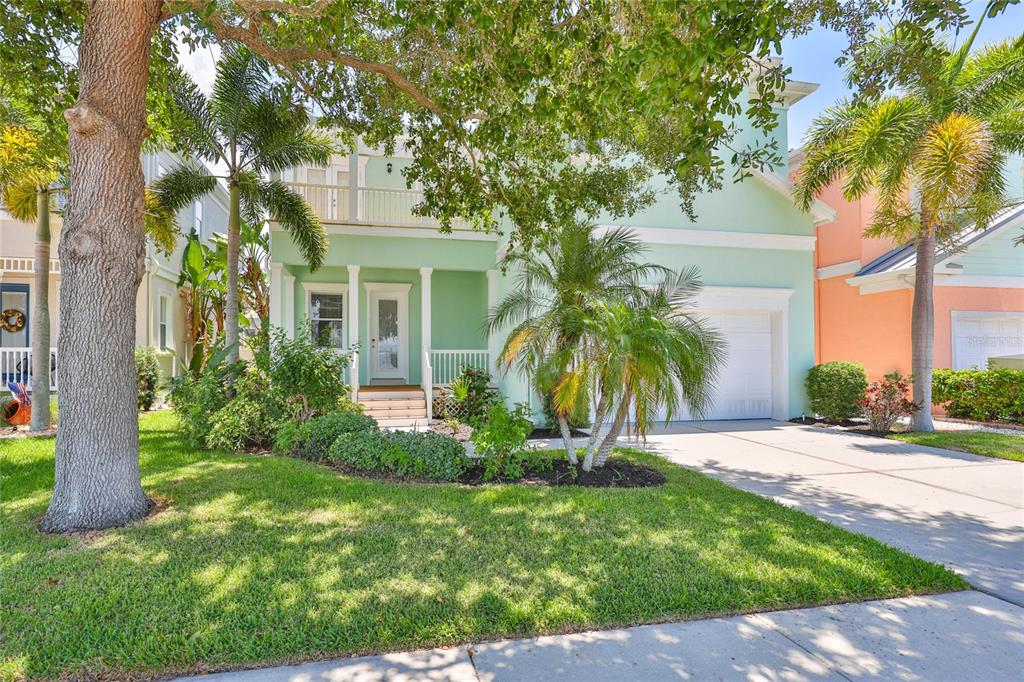 A two-story light green house with a front porch, palm trees, and a concrete driveway — 6573 SIMONE SHORES CIRCLE, APOLLO BEACH, FL