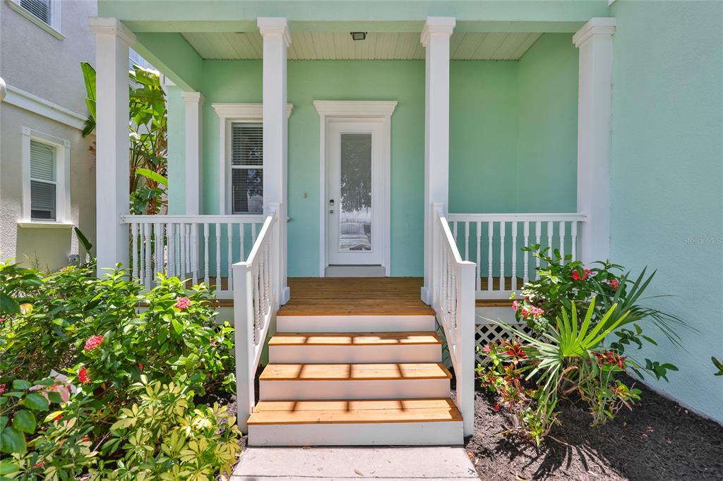 A mint green house exterior features a wooden front porch with white railings and stairs — 6573 SIMONE SHORES CIRCLE, APOLLO BEACH, FL