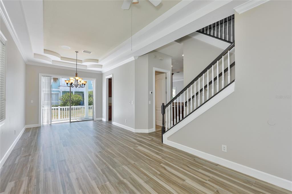 An open-concept room features wood-look tile flooring, a tray ceiling, and a staircase with railings — 6573 SIMONE SHORES CIRCLE, APOLLO BEACH, FL