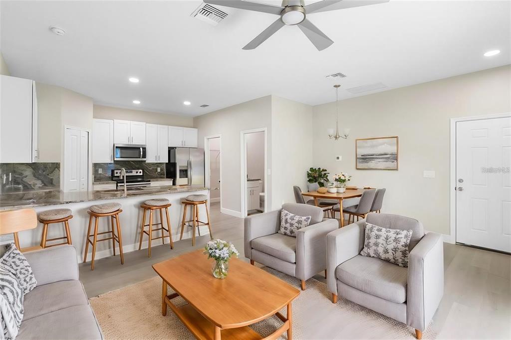 An open-concept living room, dining area, and kitchen with light wood floors and white cabinets — 1201 W 9TH STREET, SANFORD, FL