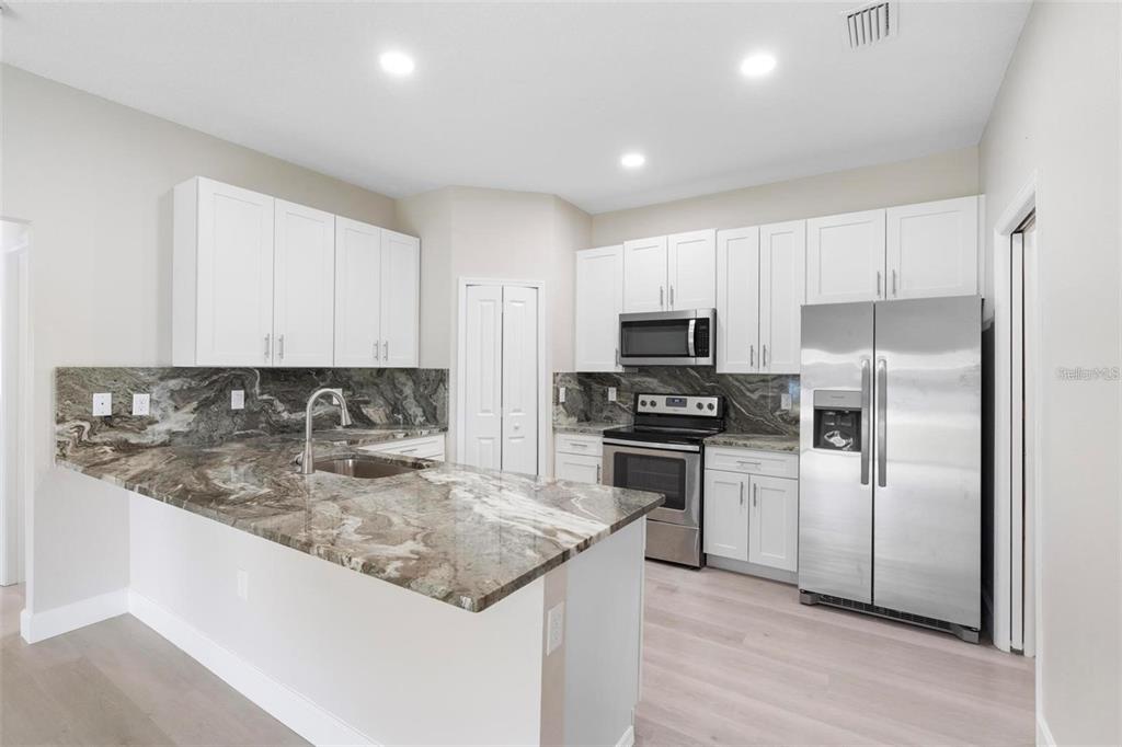 A kitchen with white cabinets, stainless steel appliances, and dark marble countertops — 1201 W 9TH STREET, SANFORD, FL