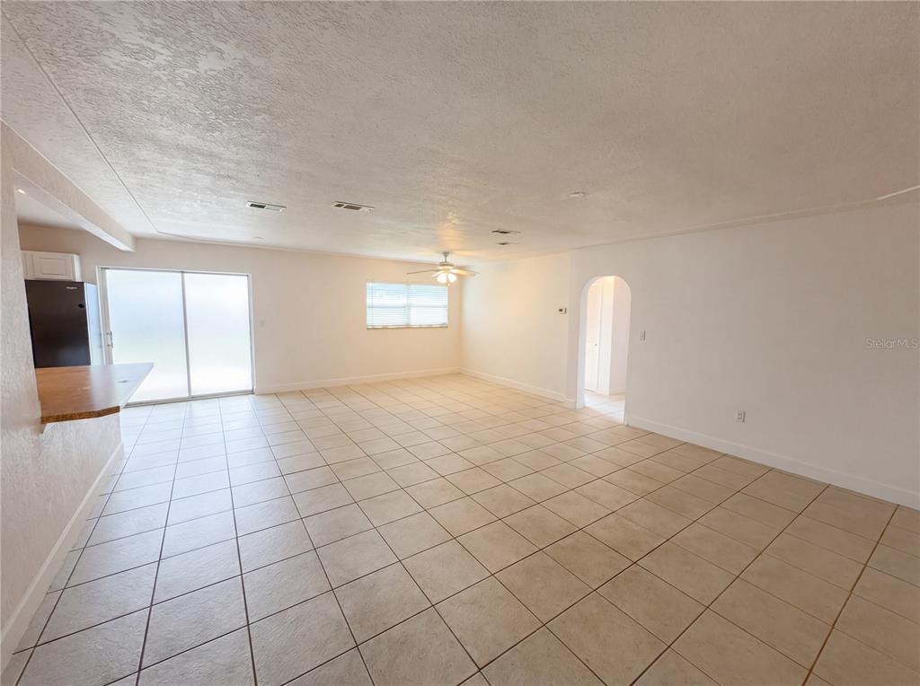 An open-concept living area features light-colored tile flooring, white walls, and a ceiling fan — 804 HAMPTON WAY, MERRITT ISLAND, FL