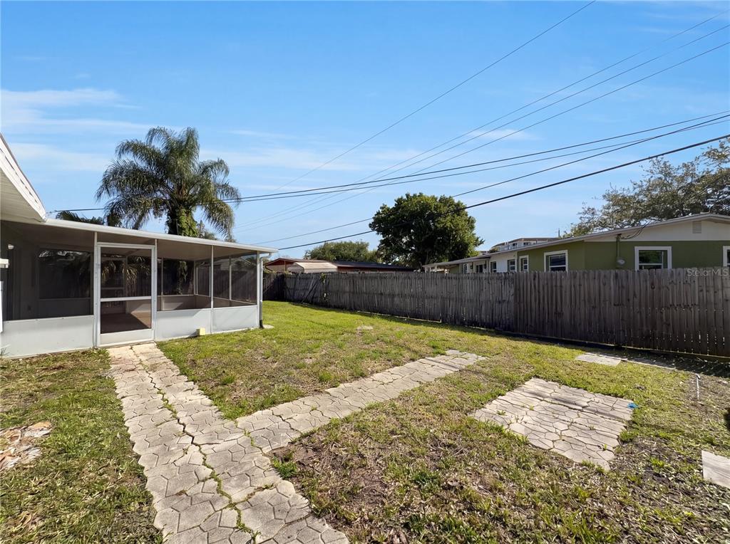 A backyard features a screened-in porch, a stone walkway, and a wooden privacy fence — 804 HAMPTON WAY, MERRITT ISLAND, FL