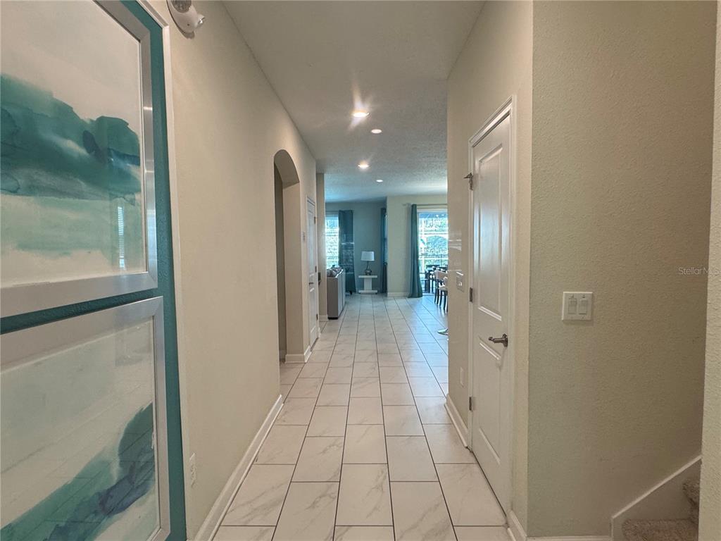 A tiled hallway leads from an entryway toward an open living area with large windows — 1580 TEMPO LANE, DAVENPORT, FL