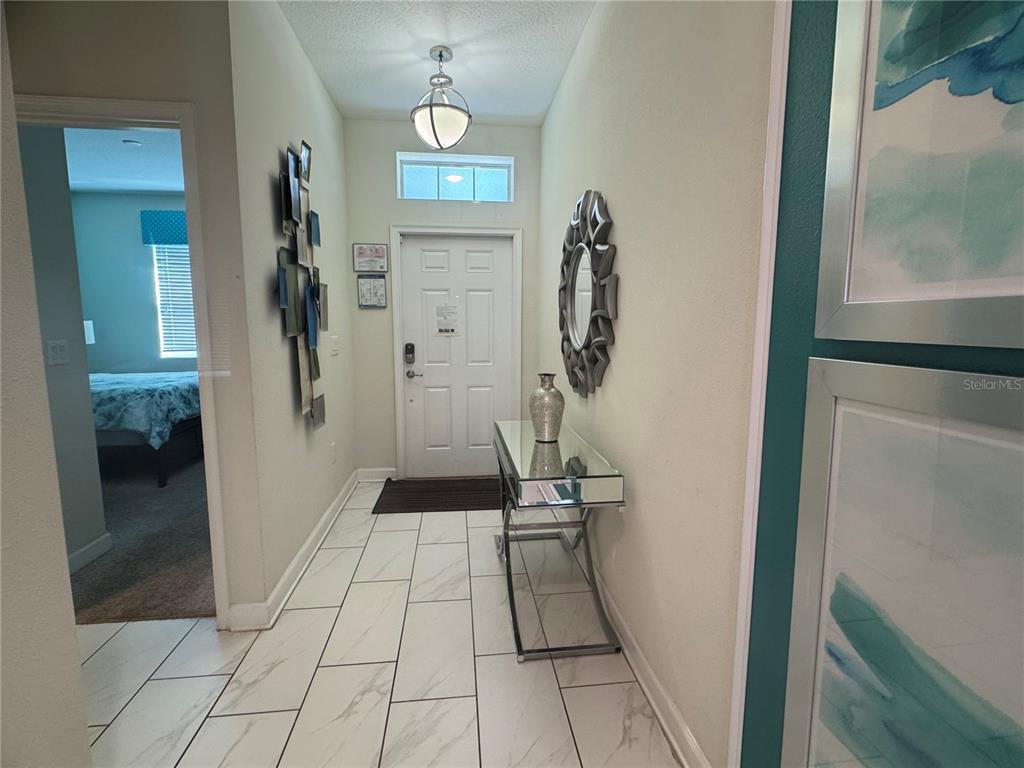 A tiled entryway features a mirrored console table, a decorative wall mirror, and a front door — 1580 TEMPO LANE, DAVENPORT, FL