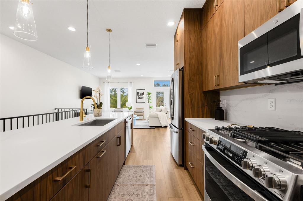 A modern kitchen features wood cabinets, white countertops, stainless steel appliances, and a breakfast island — 8627 5TH STREET N, ST PETERSBURG, FL