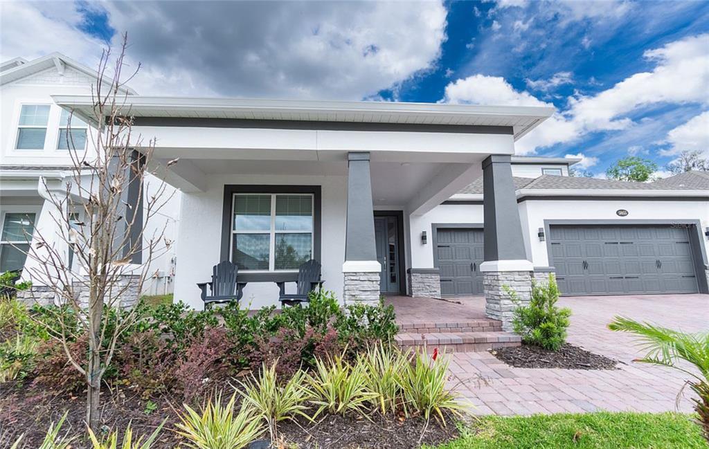 A single-story house exterior features a covered front porch, stone pillars, and a paved driveway — 5055 SHADY PINES DR, ST CLOUD, FL
