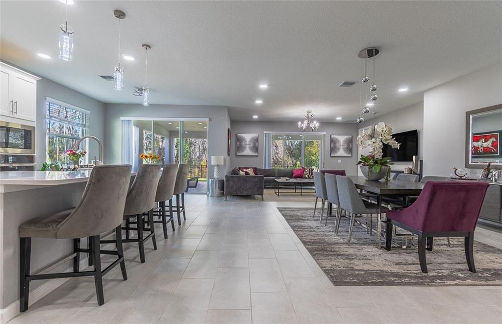 An open-concept living area features a kitchen island, dining table, and gray tile flooring — 5055 SHADY PINES DR, ST CLOUD, FL