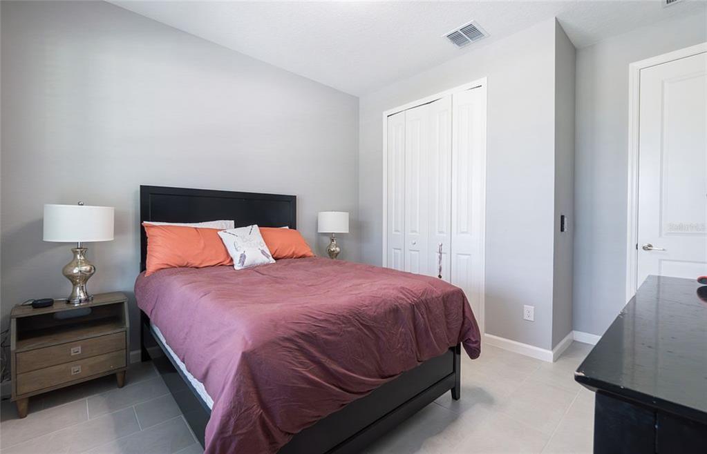 A bedroom features a black bed frame, a wooden nightstand, and white closet doors — 5055 SHADY PINES DR, ST CLOUD, FL