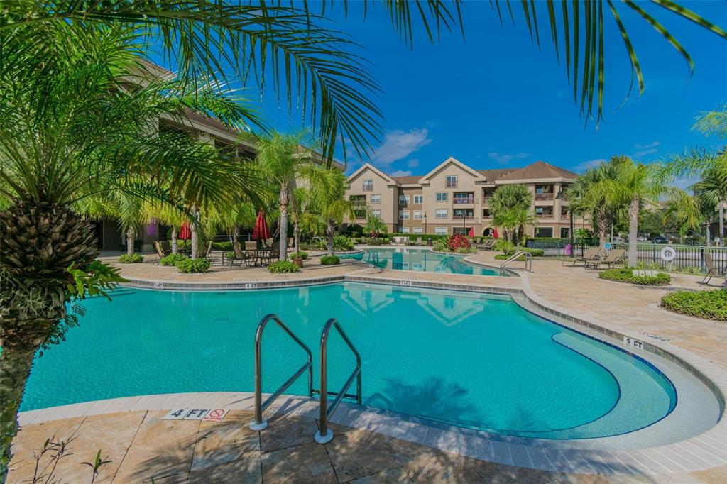 A swimming pool with a metal ladder sits in front of a multi-story apartment building — 1450 VILLA CAPRI CIRCLE UNIT 108, ODESSA, FL