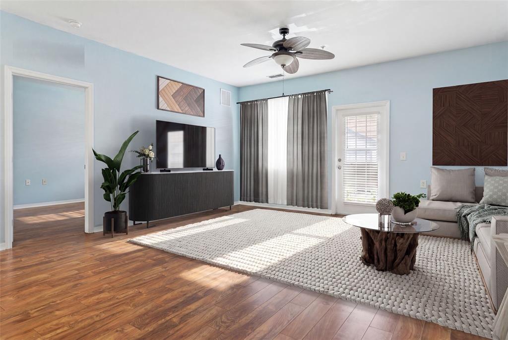 A living room features light blue walls, wood flooring, a ceiling fan, and a large rug — 1450 VILLA CAPRI CIRCLE UNIT 108, ODESSA, FL