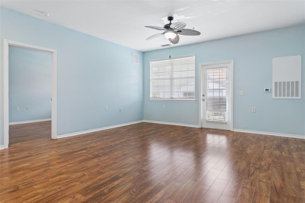 An empty room with light blue walls, wood-look flooring, a ceiling fan, and a door — 1450 VILLA CAPRI CIRCLE UNIT 108, ODESSA, FL
