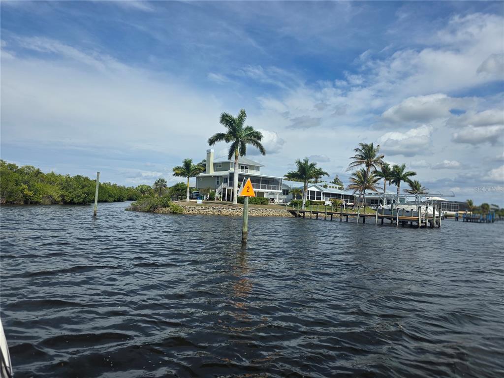 A waterfront house with a dock and palm trees viewed from the water — 3796 PEACE RIVER DRIVE, PUNTA GORDA, FL