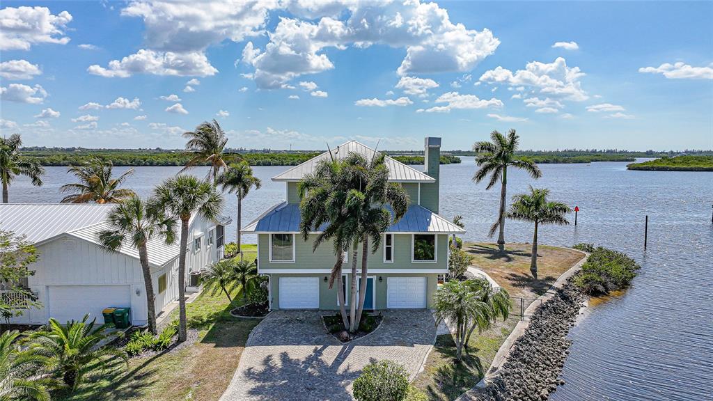 An aerial view shows a two-story waterfront house with a metal roof and palm trees — 3796 PEACE RIVER DRIVE, PUNTA GORDA, FL
