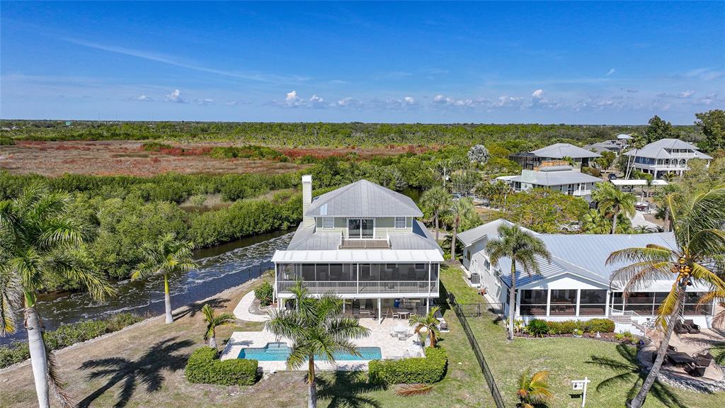 An aerial view of a multi-story house with a pool, deck, and surrounding marshland — 3796 PEACE RIVER DRIVE, PUNTA GORDA, FL