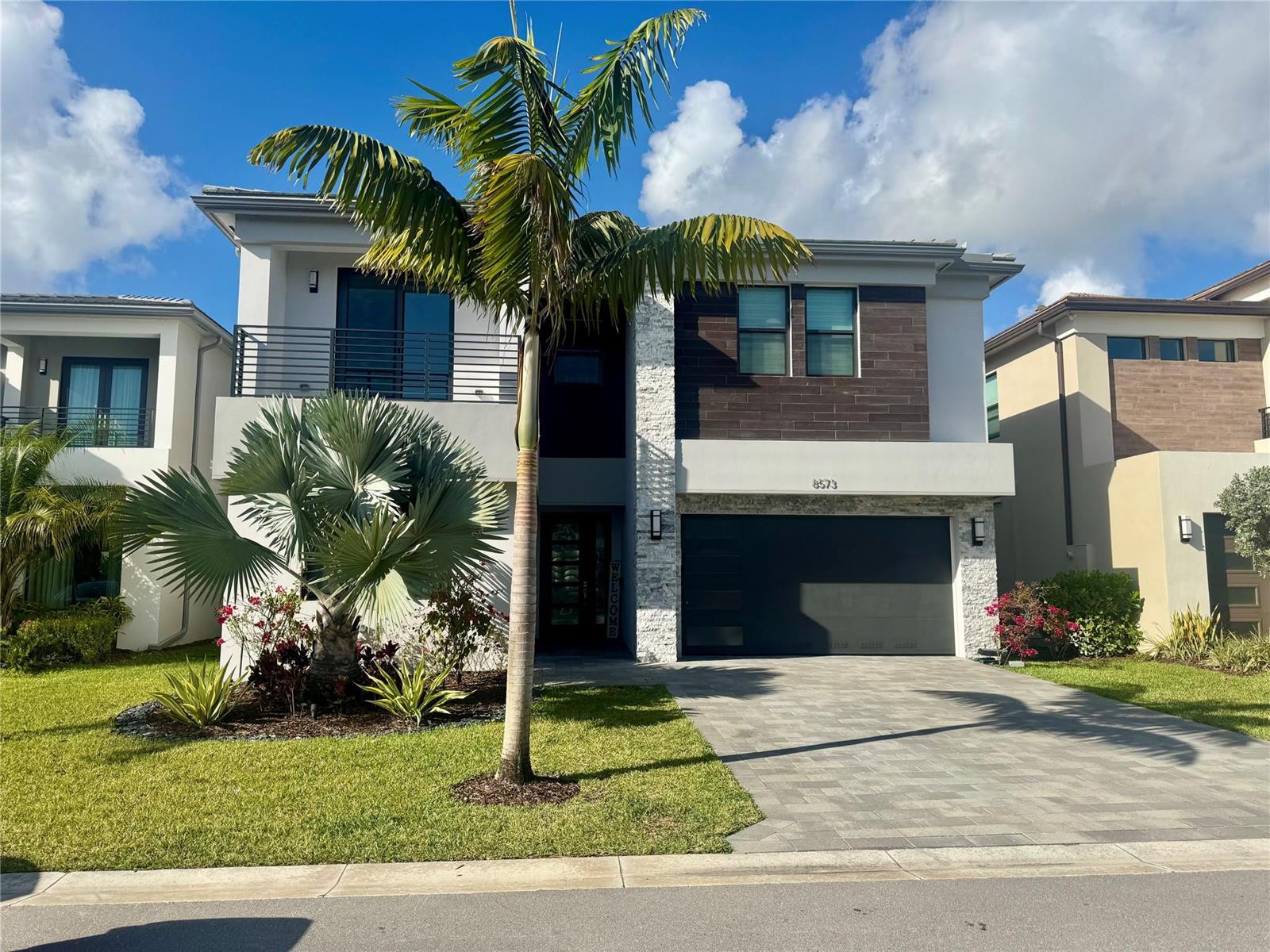 A two-story modern house features a stone facade, a dark garage, and a palm tree — 8573 Crystal Downs Avenue, Boca Raton FL 33434, BOCA RATON, FL