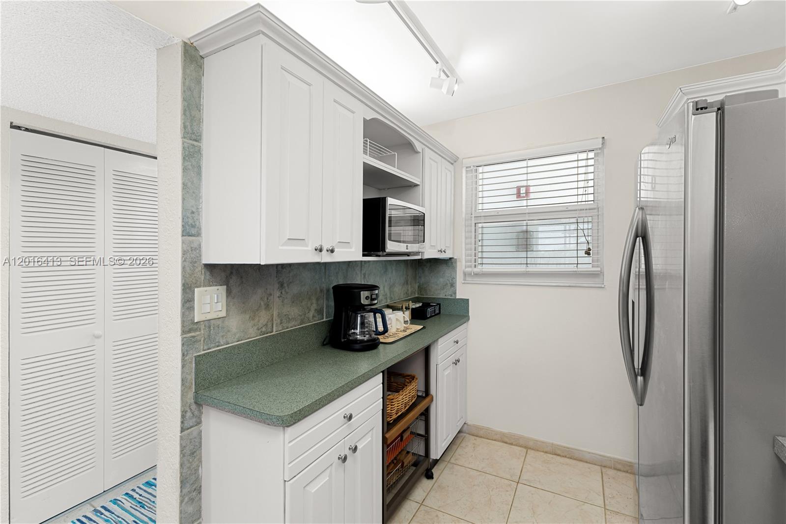 A kitchen features white cabinets, a green countertop, a microwave, and a stainless steel refrigerator — 1391 S Ocean Blvd # 409, Pompano Beach FL 33062, POMPANO BEACH, FL