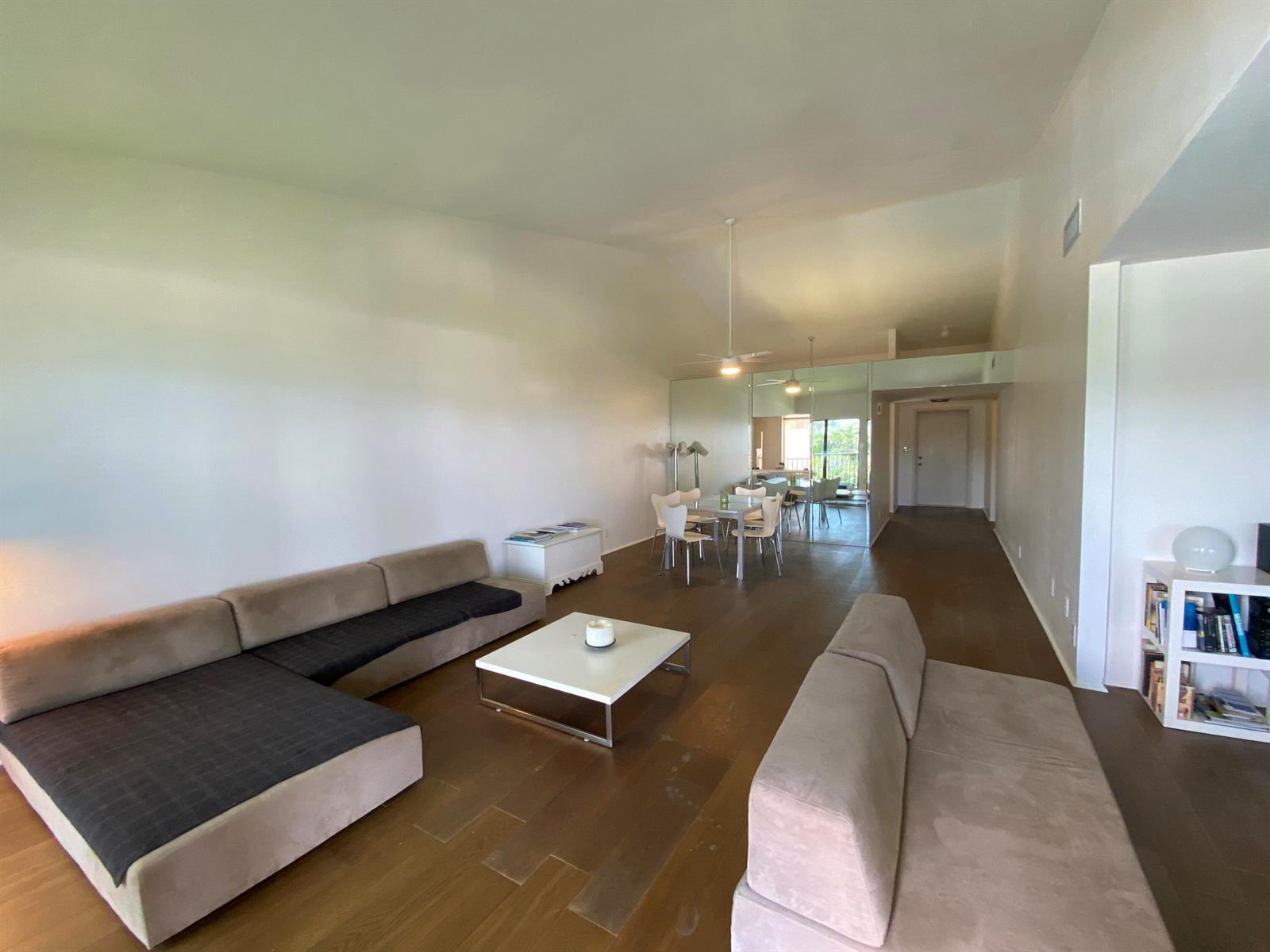 A spacious living room features hardwood floors, a sectional sofa, and a dining area — 5801 N Ocean Boulevard # 208, Ocean Ridge FL 33435, OCEAN RIDGE, FL