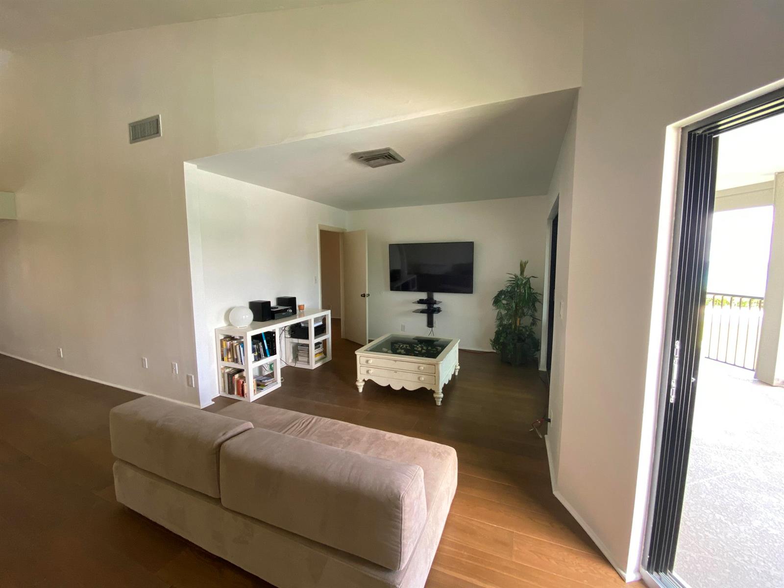 A living room features wood flooring, a beige sofa, a white coffee table, and a television — 5801 N Ocean Boulevard # 208, Ocean Ridge FL 33435, OCEAN RIDGE, FL