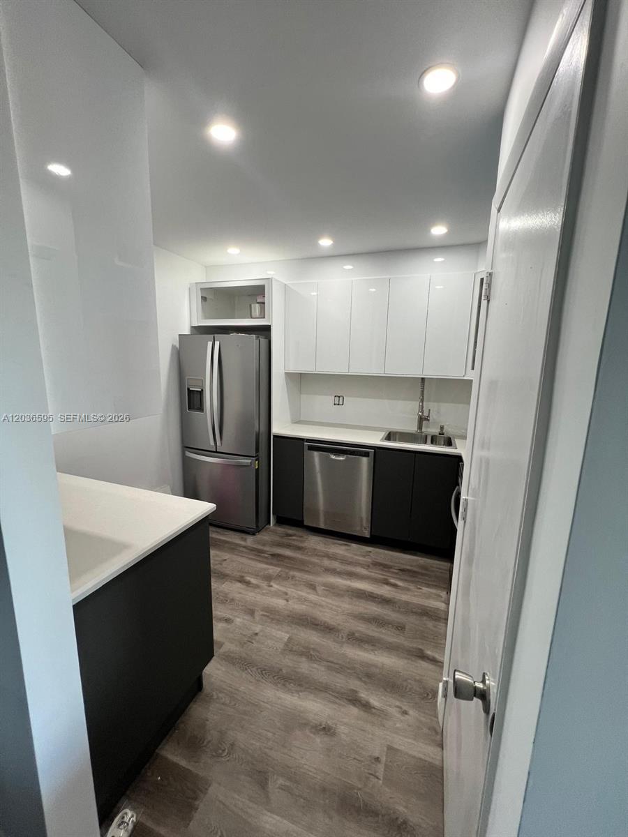 A kitchen area features white upper cabinets, dark gray lower drawers, and under-cabinet lighting — 4164 INVERRARY DR # 1004, Lauderhill FL 33319, LAUDERHILL, FL
