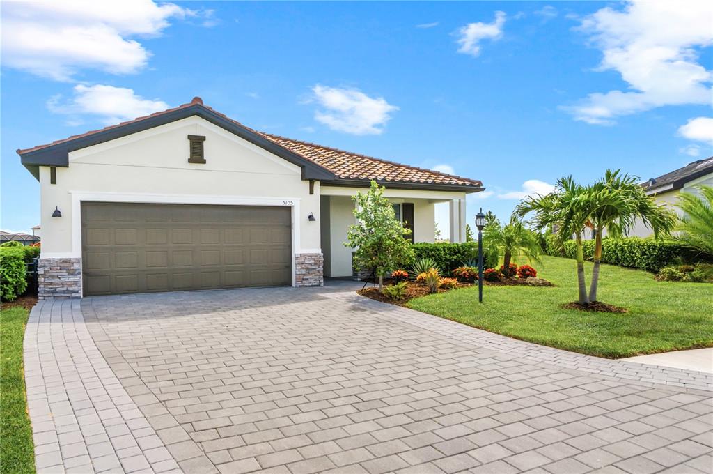 A single-story house with a tiled roof, stone accents, and a paved driveway — 5105 MARINA BASIN COURT, BRADENTON, FL
