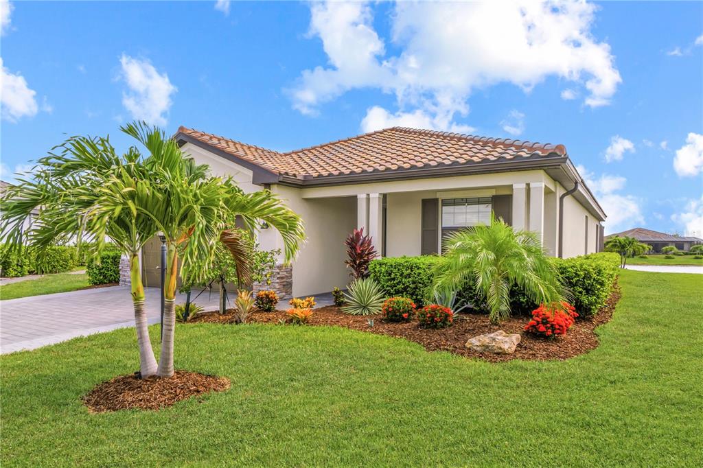 A single-story house with a tiled roof, a paved driveway, and landscaped front yard — 5105 MARINA BASIN COURT, BRADENTON, FL