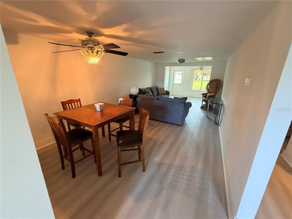 A dining area with a wooden table and chairs leads into a living room — 4446 RUSTIC DRIVE UNIT E, NEW PORT RICHEY, FL