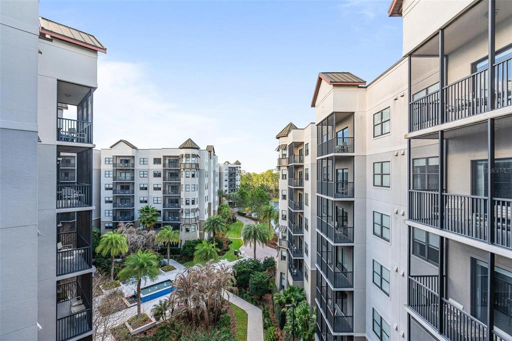 An exterior view of multi-story apartment buildings with screened balconies overlooking a landscaped courtyard — 14501 GROVE RESORT AVENUE UNIT 1629, WINTER GARDEN, FL