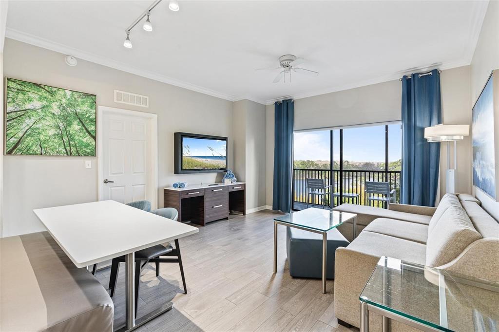 A living and dining area features a sofa, table, television, and a balcony view — 14501 GROVE RESORT AVENUE UNIT 1629, WINTER GARDEN, FL