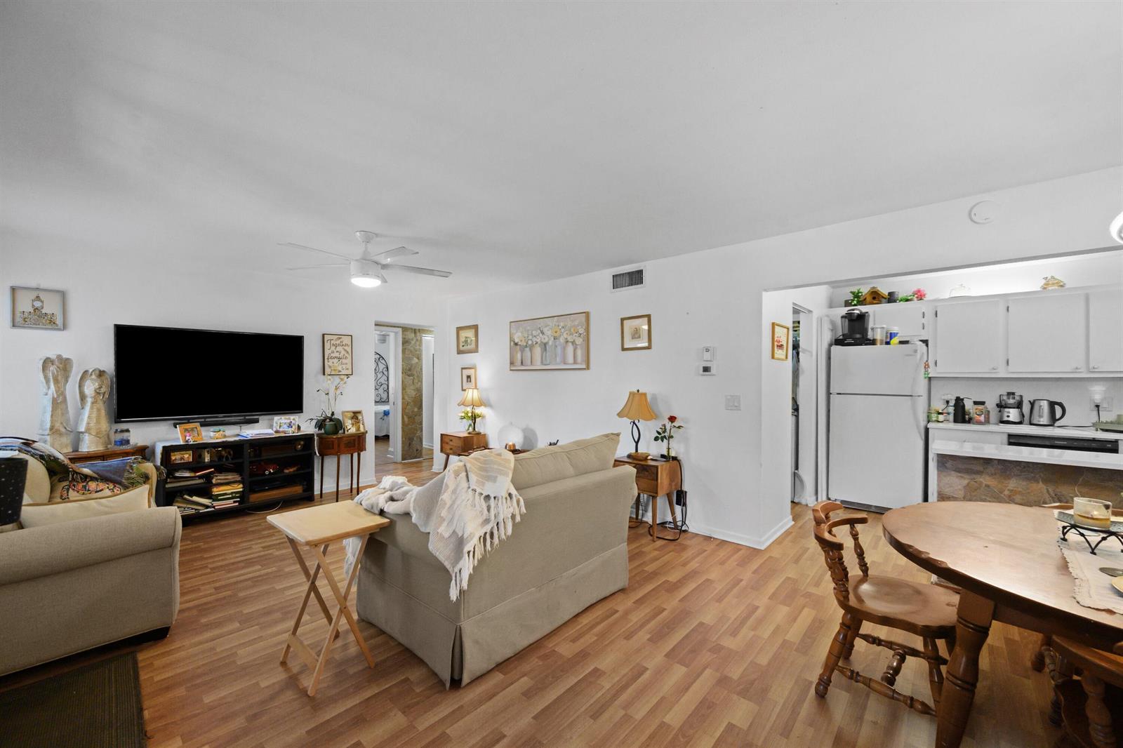 A living room with wood-look flooring, a beige sofa, and an adjacent kitchen area — 431 Pine Glen Lane # 2, FL 33463, FL