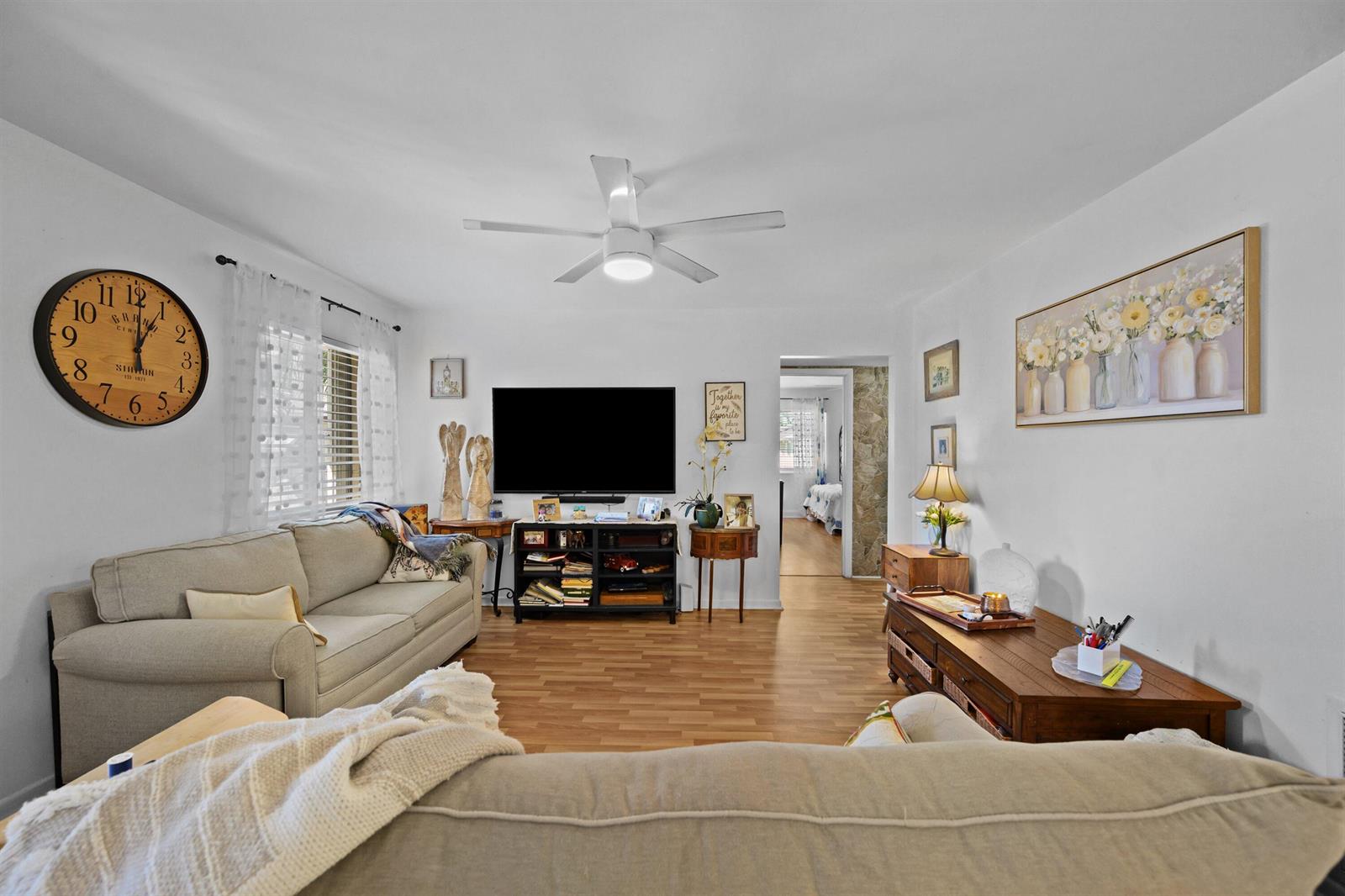 A living room features a beige sofa, a television on a media console, and wood-look flooring — 431 Pine Glen Lane # 2, FL 33463, FL