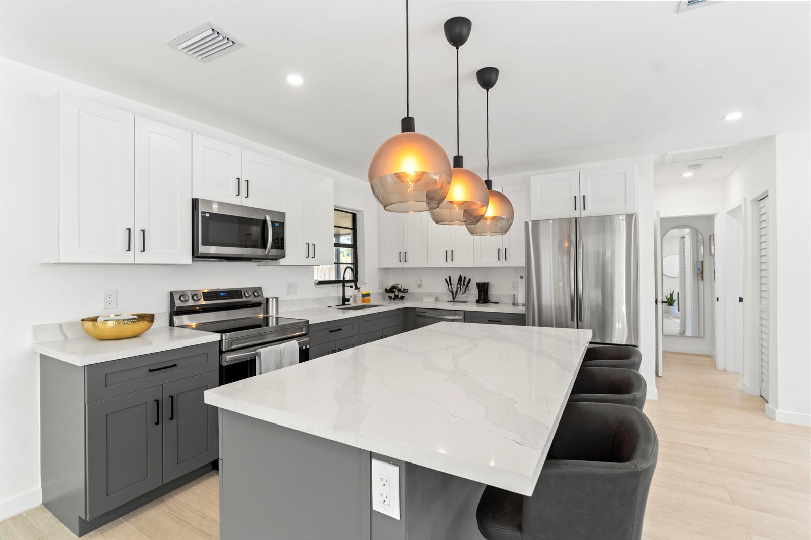 A modern kitchen features white upper cabinets, gray lower cabinets, a quartz island, and pendant lighting — 235 NE 20th Street, Boca Raton FL 33431, BOCA RATON, FL