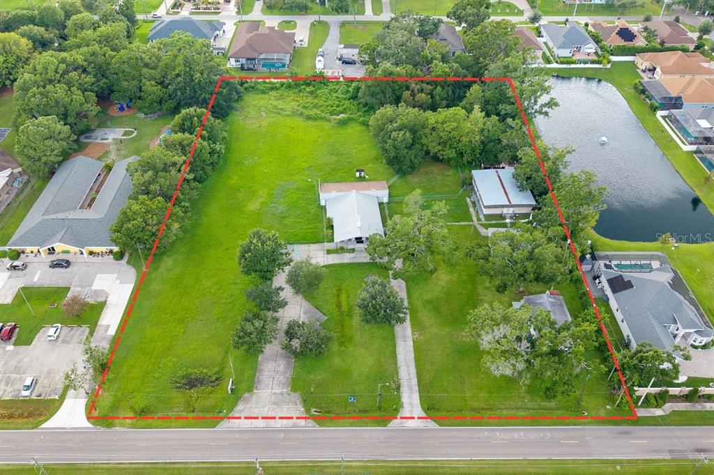 An aerial view shows a large, grassy lot with two buildings and two driveways — 15402 CASEY ROAD, TAMPA, FL