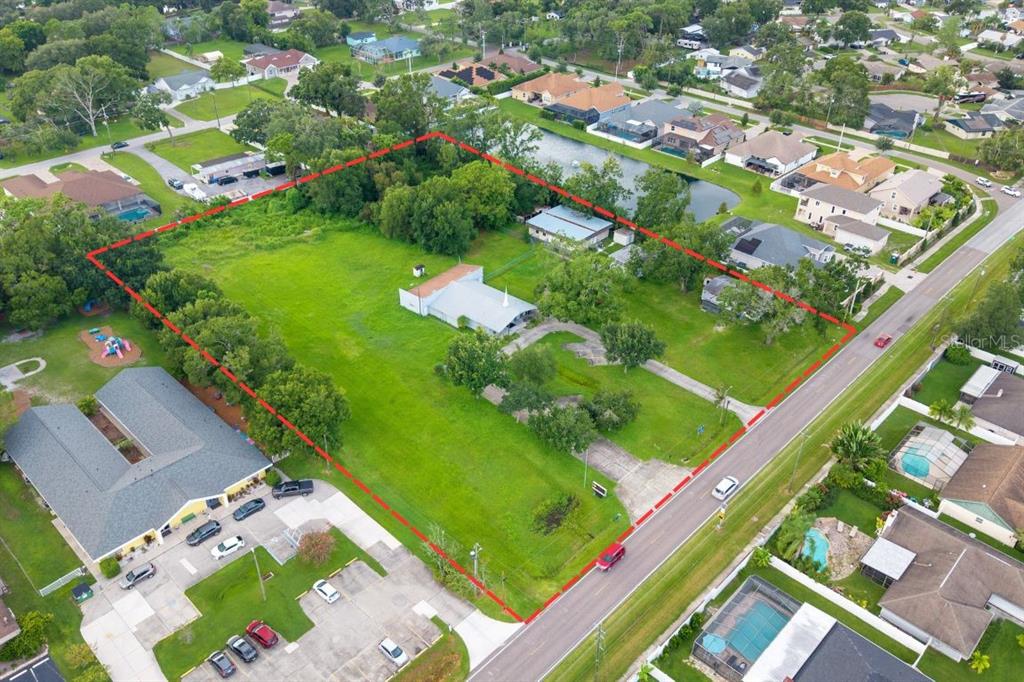 An aerial view shows a large, grassy lot with a church building and parking area — 15402 CASEY ROAD, TAMPA, FL