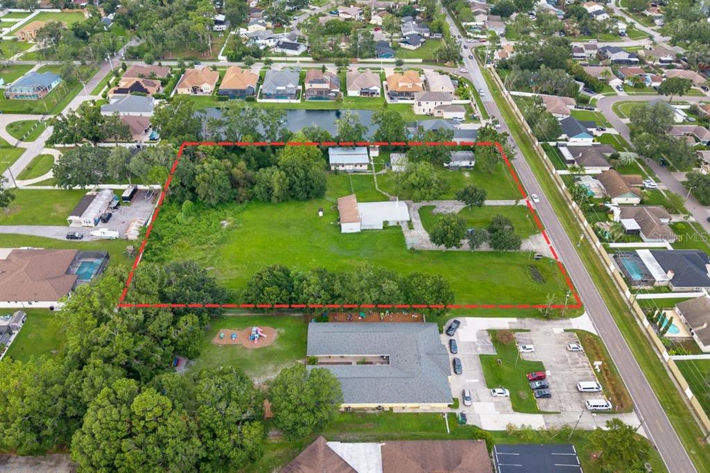 An aerial view shows a large, rectangular grassy lot outlined in red with two houses — 15402 CASEY ROAD, TAMPA, FL