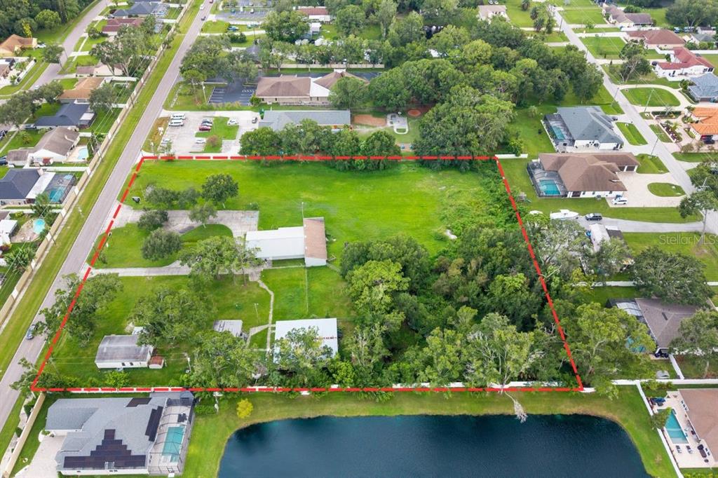 An aerial view shows a large, rectangular residential lot outlined in red bordering a lake — 15402 CASEY ROAD, TAMPA, FL