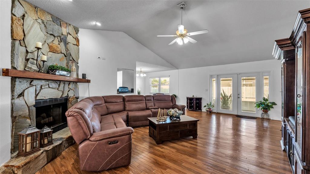 A living room features a stone fireplace, brown sectional sofa, and hardwood flooring — 5249 NICHOLS DRIVE W, LAKELAND, FL