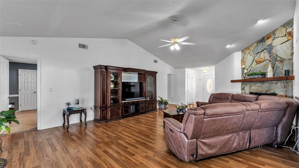 A living room features wood-look flooring, a stone fireplace, and a large dark wood entertainment center — 5249 NICHOLS DRIVE W, LAKELAND, FL