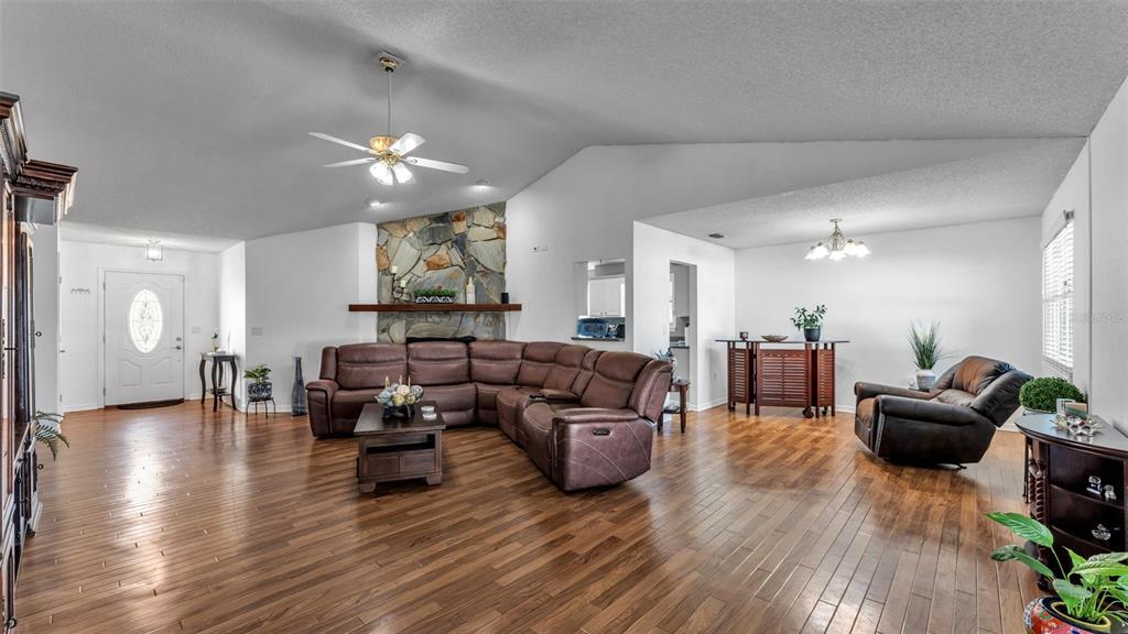 A spacious living room features wood flooring, a stone fireplace, and a large brown sectional — 5249 NICHOLS DRIVE W, LAKELAND, FL