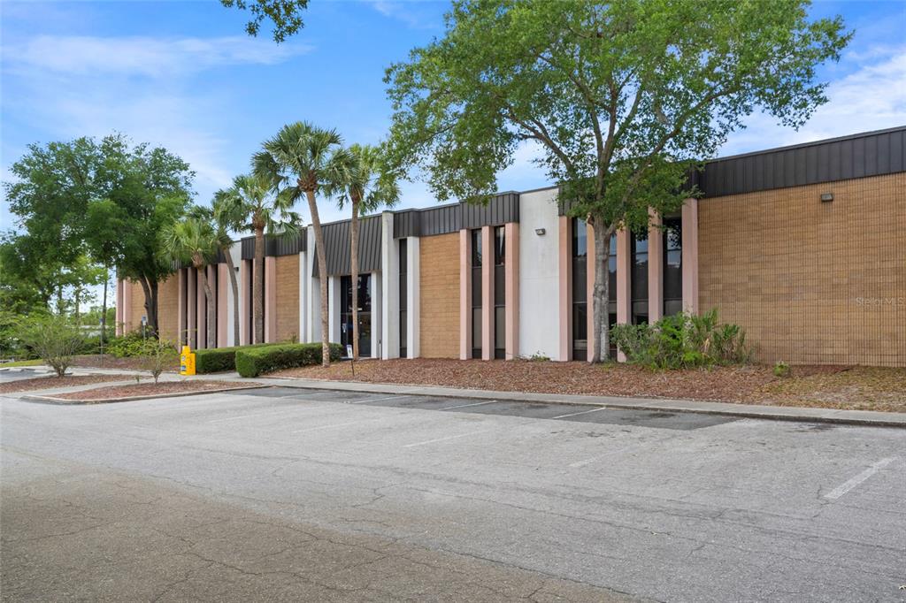 A low-rise commercial building with a tan brick facade, dark metal trim, and palm trees — 1624 N MEADOWCREST BOULEVARD UNIT 3, CRYSTAL RIVER, FL