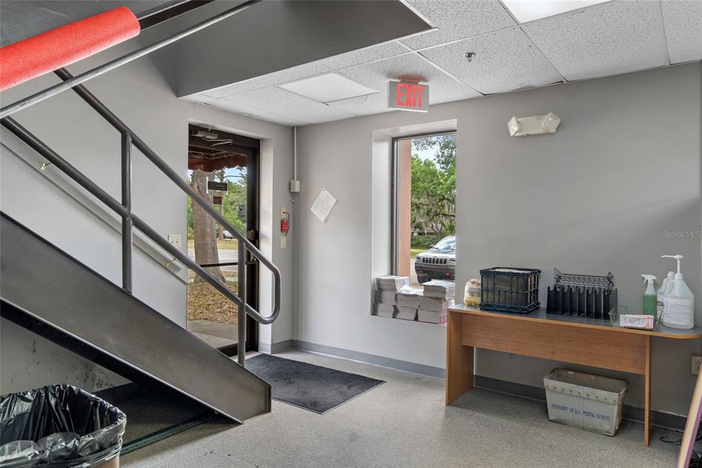 An interior view of a commercial entryway featuring a staircase, an exit door, and a desk — 1624 N MEADOWCREST BOULEVARD UNIT 3, CRYSTAL RIVER, FL