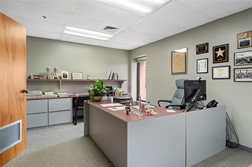 An office features a large desk, a rolling chair, wall-mounted awards, and a storage cabinet — 1624 N MEADOWCREST BOULEVARD UNIT 3, CRYSTAL RIVER, FL