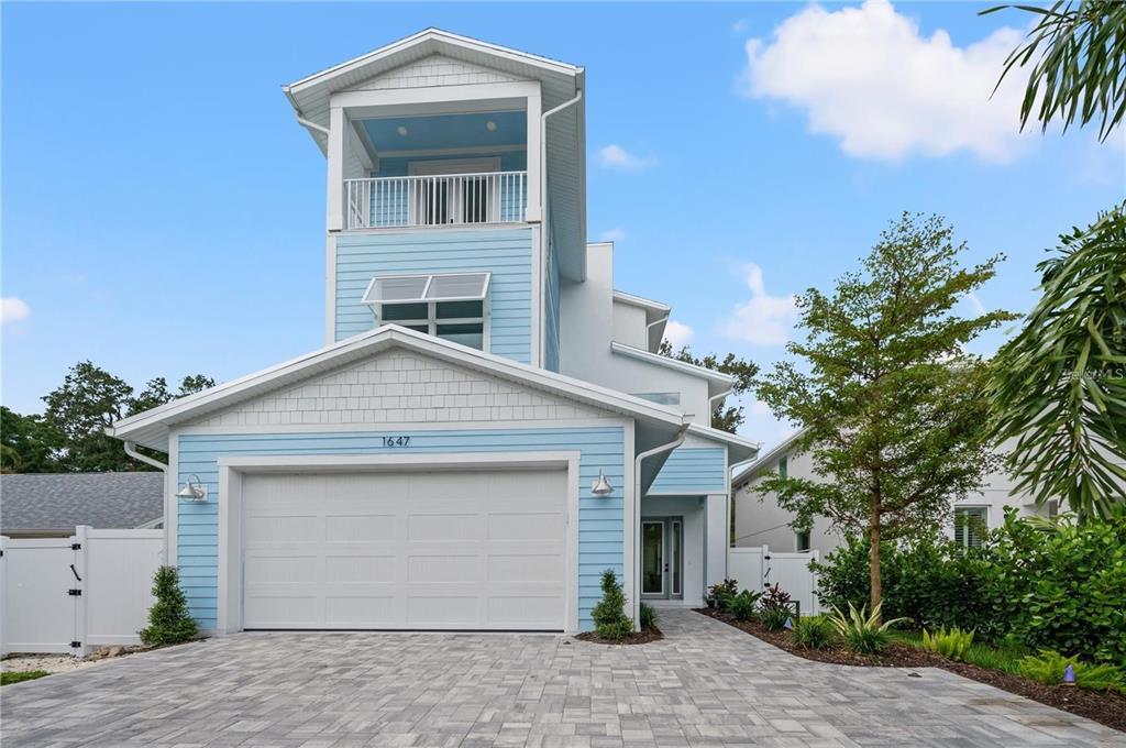 A light blue two-story house with a garage and a balcony under a clear sky — 1647 SIESTA DRIVE, SARASOTA, FL